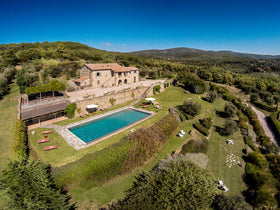 Cortona villa - Aerial view of a villa with a pool surrounded by greenery.