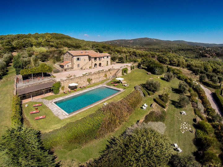 Cortona villa - Aerial view of a villa with a pool surrounded by greenery.